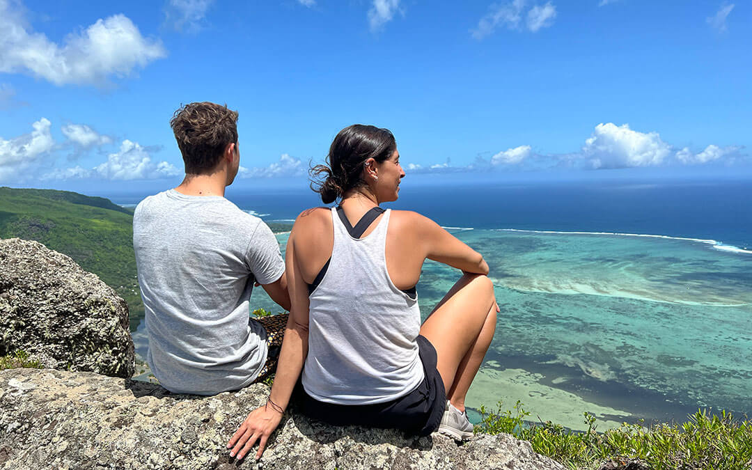 Young man and woman on hike overlooking Brazilian coastline from mountain