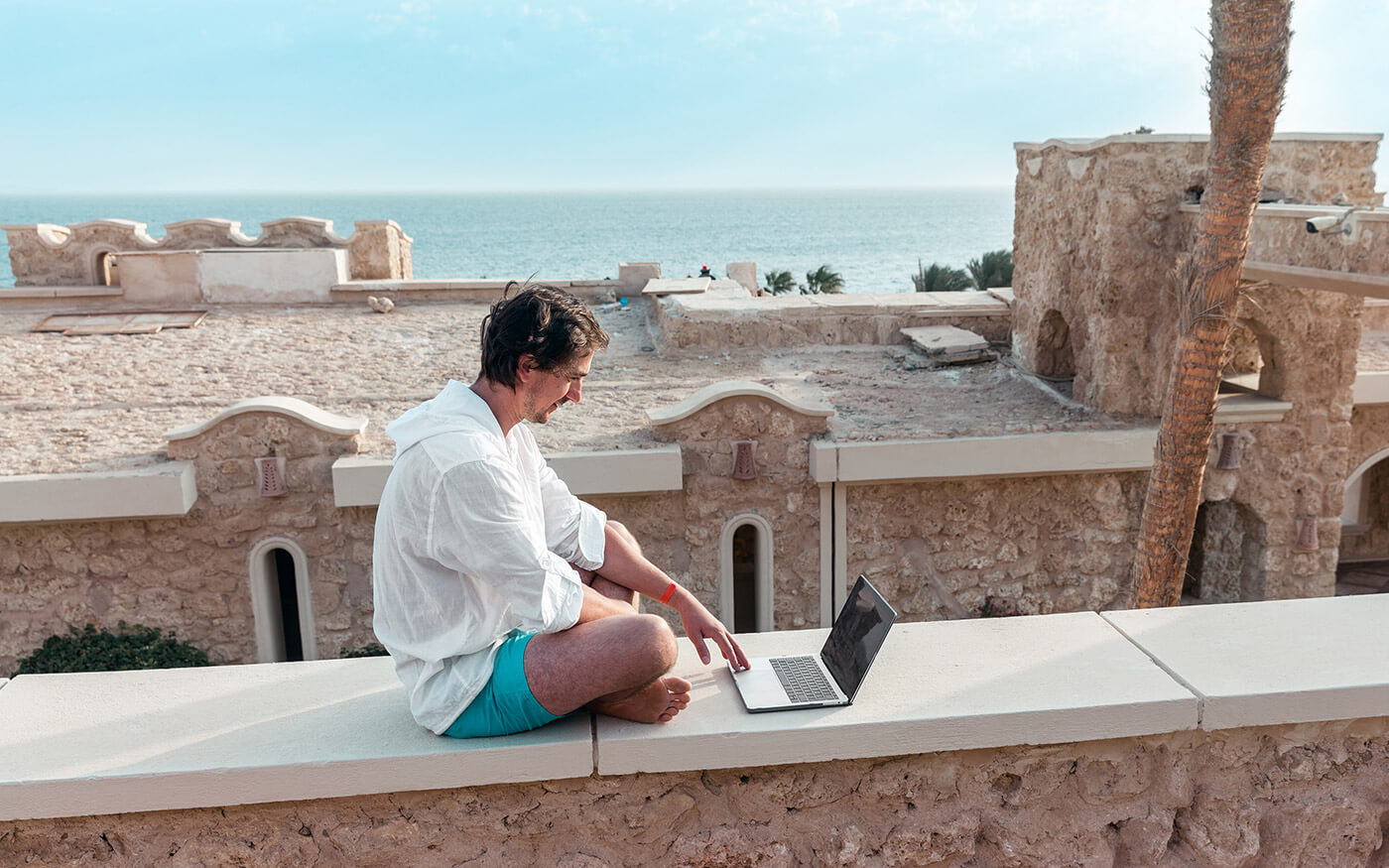 Man working on laptop near the beach