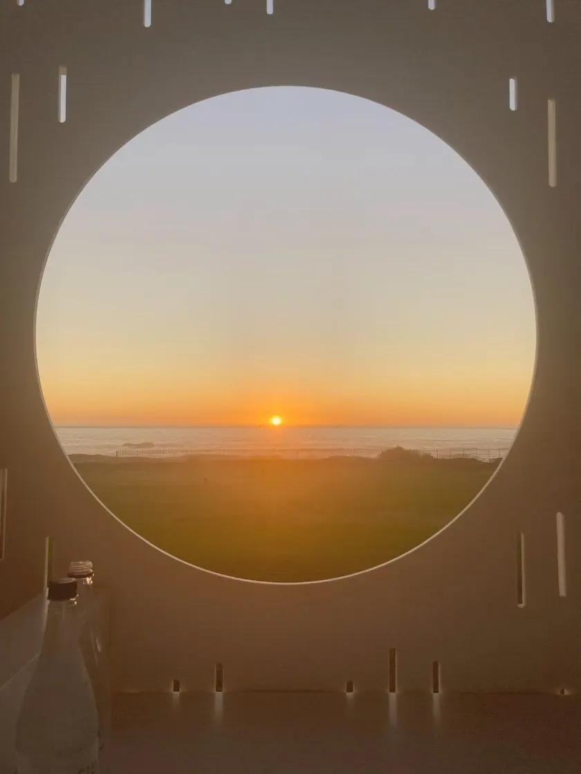 Sunset over the ocean framed by a round window in Cape Town, South Africa