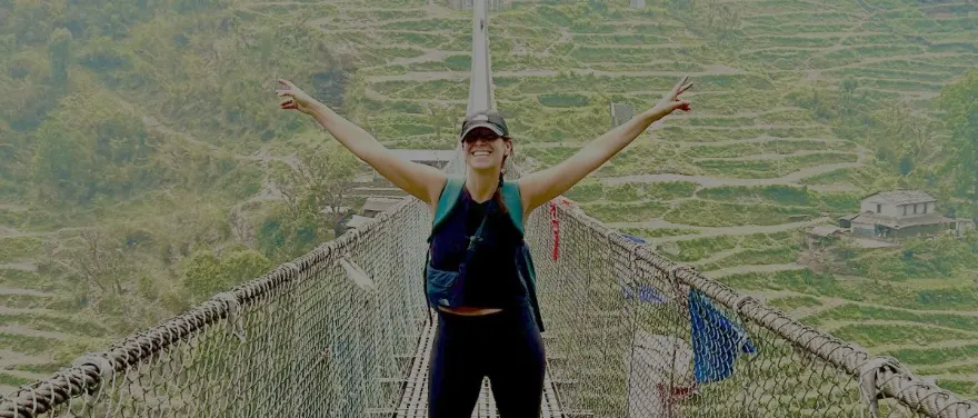 Traveler celebrating on a long suspension bridge over green terraced hills in Sri Lanka