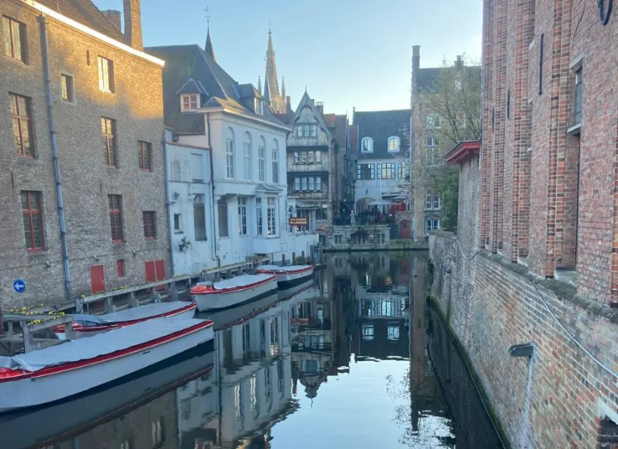 Canal lined with historic gabled houses and moored boats in Bruges, Belgium
