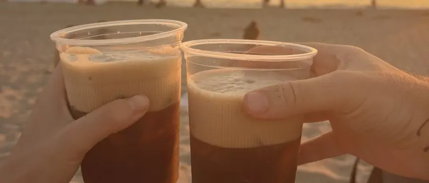Two cold brews toasting at sunset on the beach in Puerto Escondido, Mexico