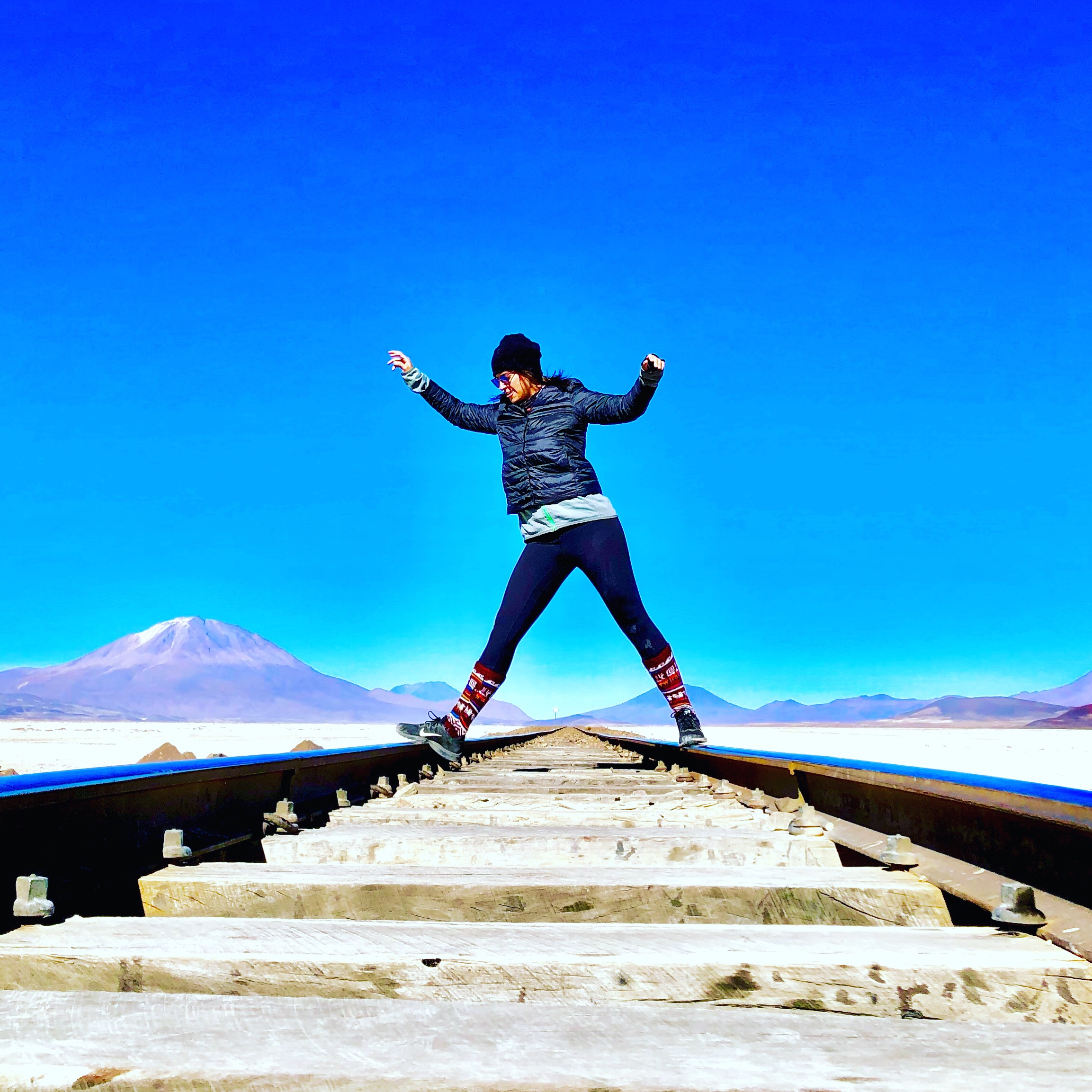 Traveller balancing on railway tracks across the Salar de Uyuni salt flat, Bolivia